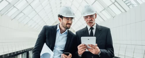 two-successful-entrepreneur-helmet-with-project-laptop-new-buildings-stay-near-glass-roof_496169-971